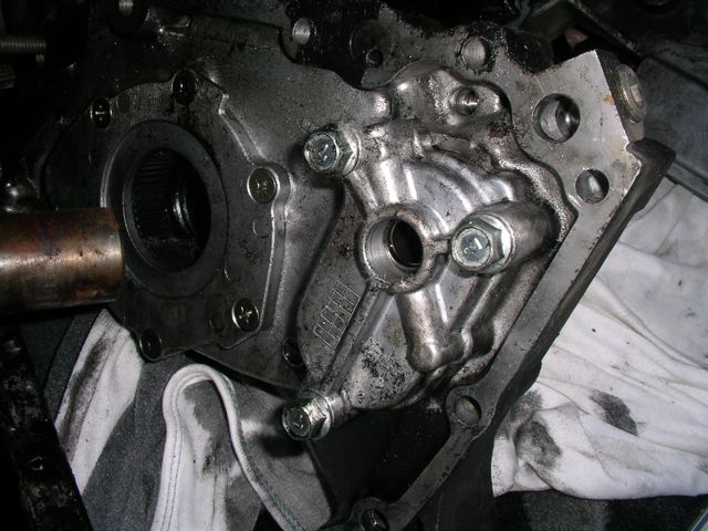 Backside of front engine cover showing the oil pump and the drive (hole in the top of the pump) that runs the balance shaft.
